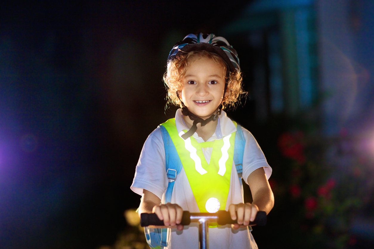 Child riding a scooter in reflective clothing