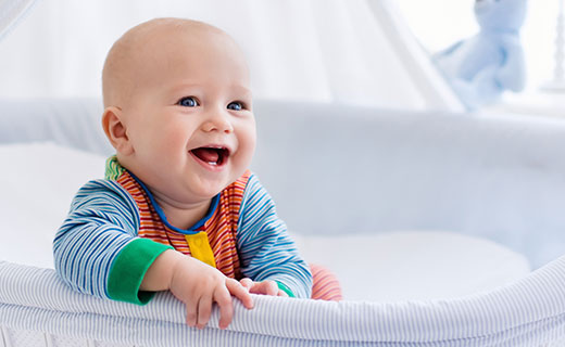 Smiling happy young baby in his white cot