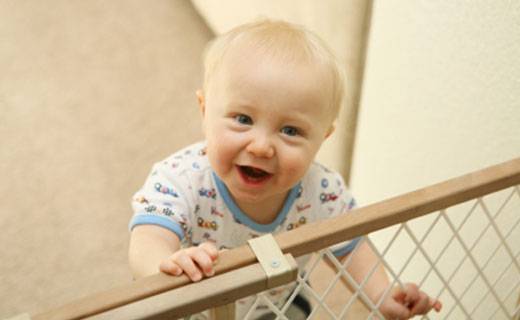 baby smiling standing at gate