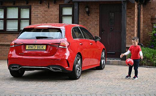 Child playing on driveway with a parked car