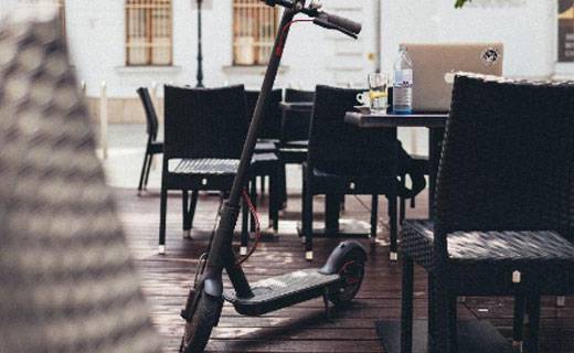 Electric scooter perched up against a set of chairs and tables