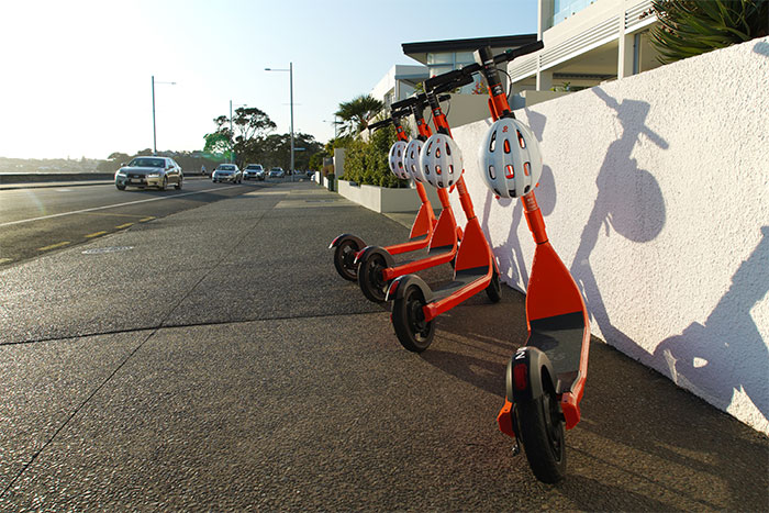 A row of brightly coloured e-scooters lined up on the pavement