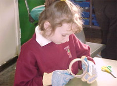 A student tries to pick apart tape wearing safety gloves