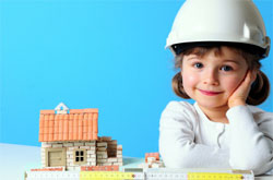 A picture of a child wearing a hard hat with a model house.
